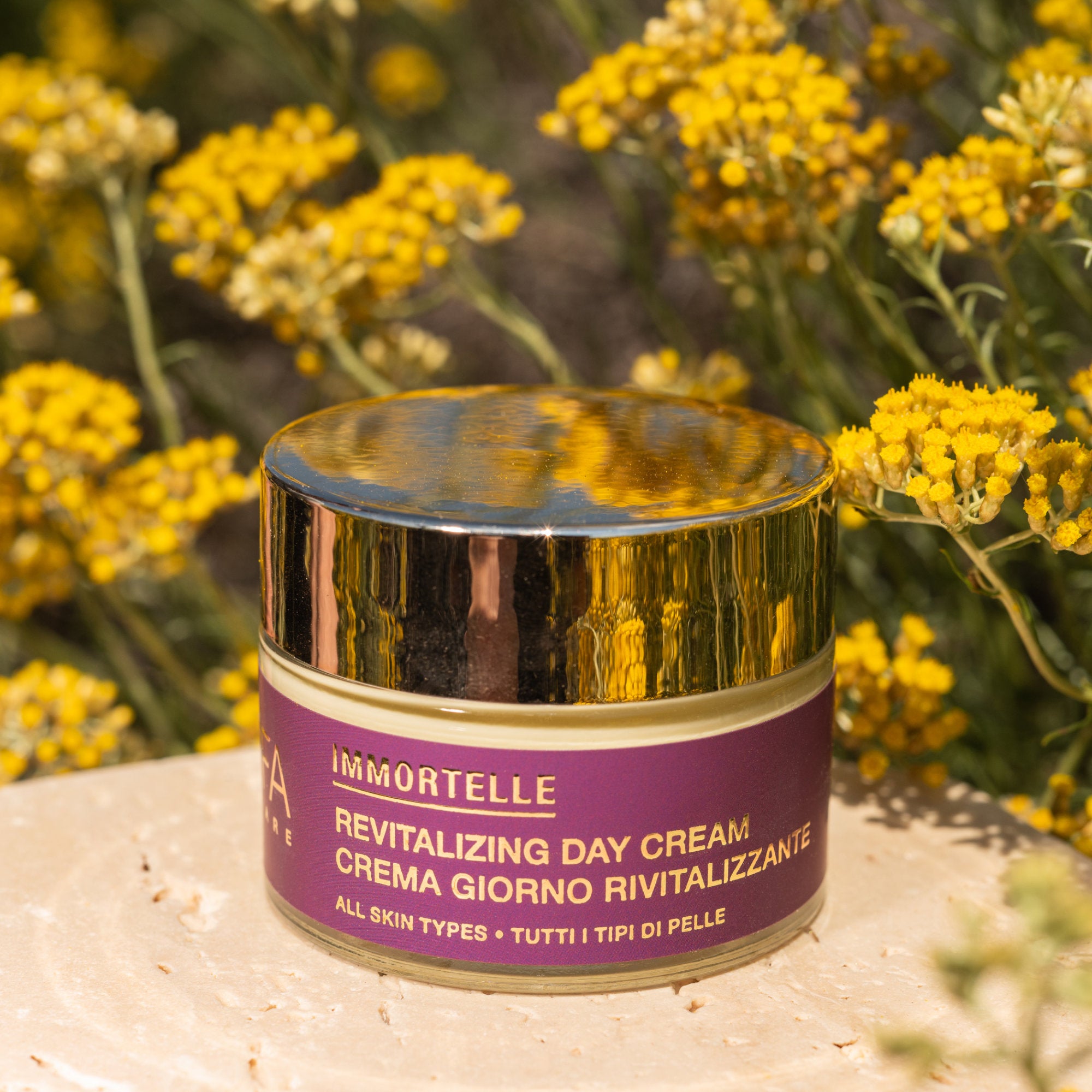 Primo piano della crema viso all’elicriso di Ninfa Skincare con sfondo di campo di elicriso italico in fiore