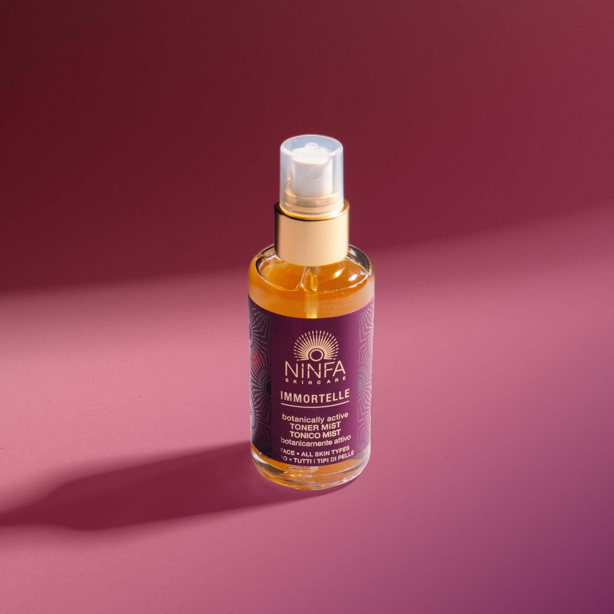 Primo piano del tonico viso all’elicriso di Ninfa Skincare su sfondo rosa scuro