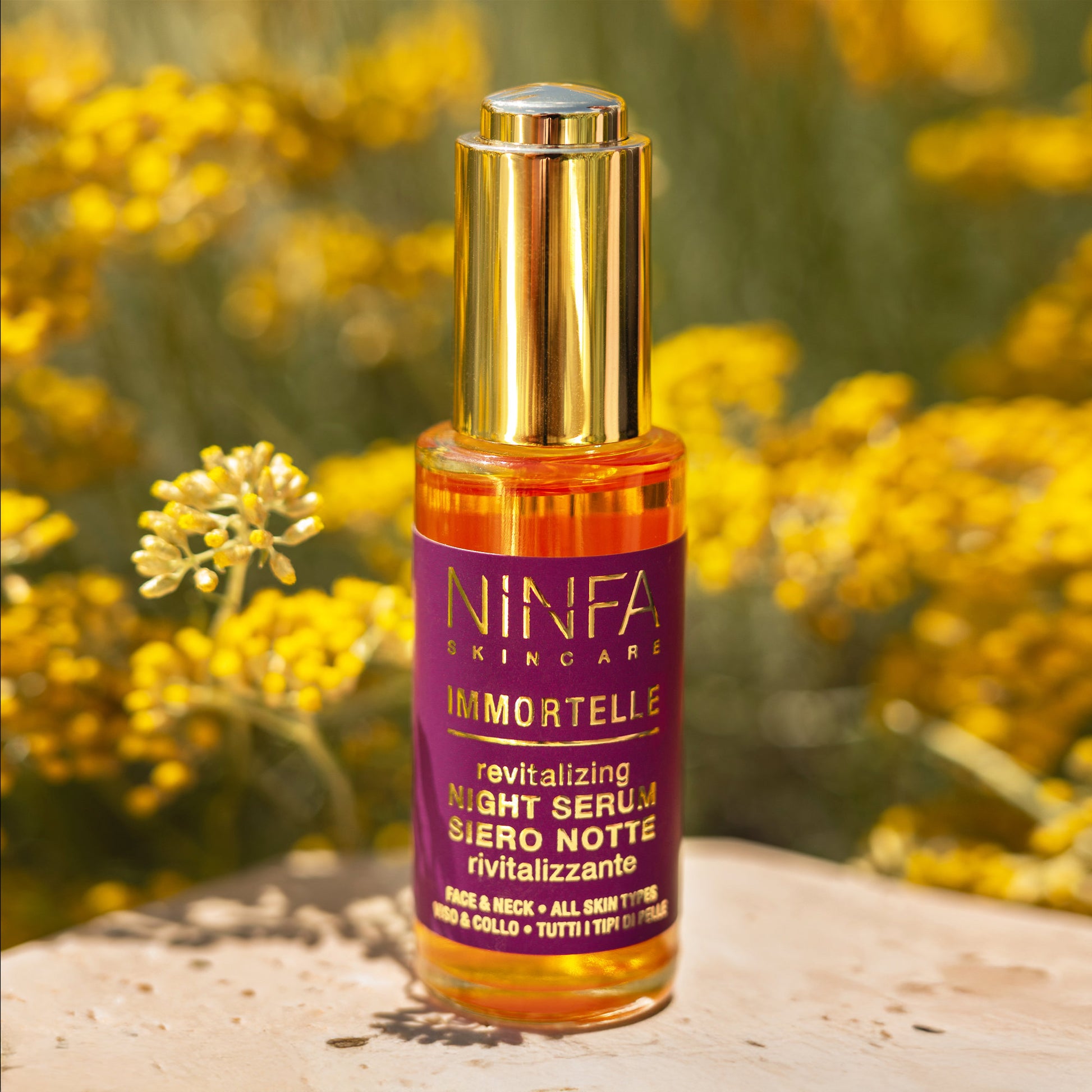 Primo piano del siero all’elicriso di Ninfa Skincare con sfondo di campo di elicriso italico in fiore