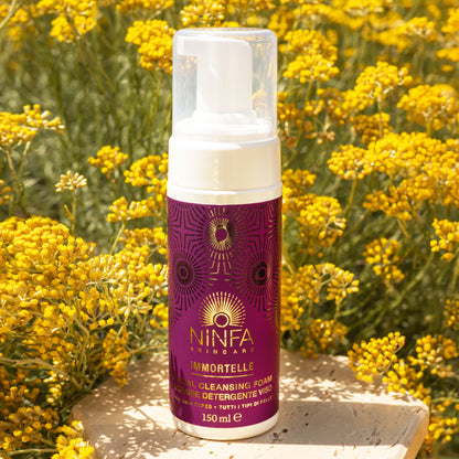 Primo piano della mousse detergente all’elicriso di Ninfa Skincare con sfondo di campo di elicriso italico in fiore